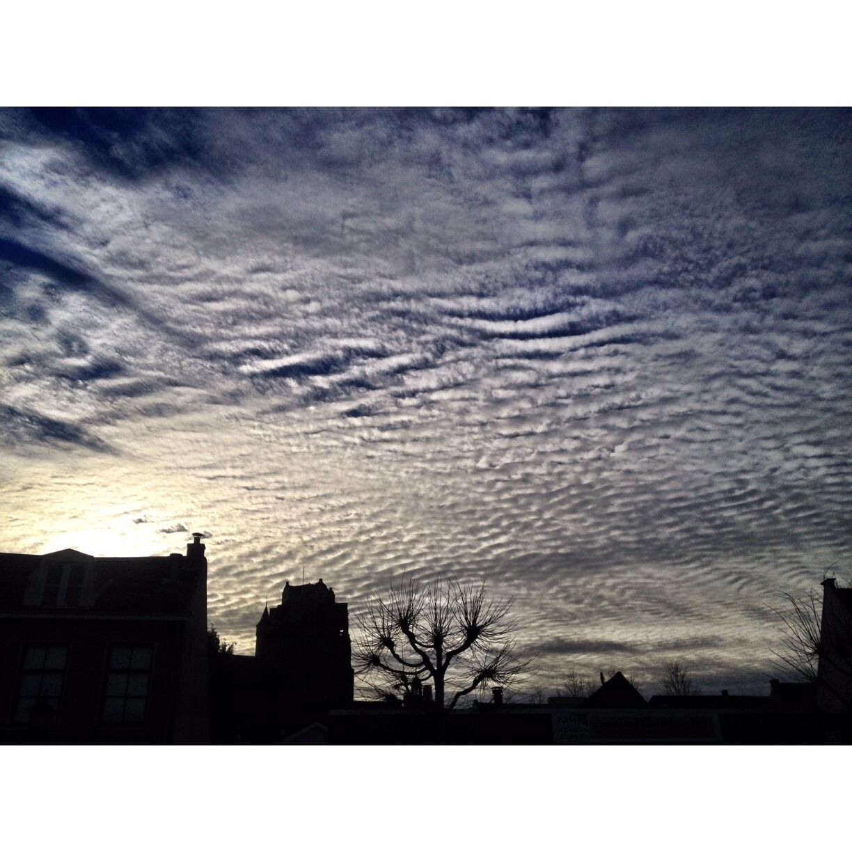 A sunset with a cloud pattern over a cityscape.