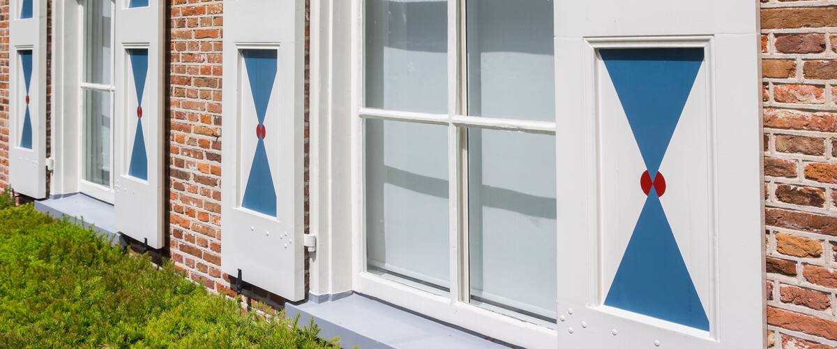 A row of windows with blue and red diamond patterns on a brick building.