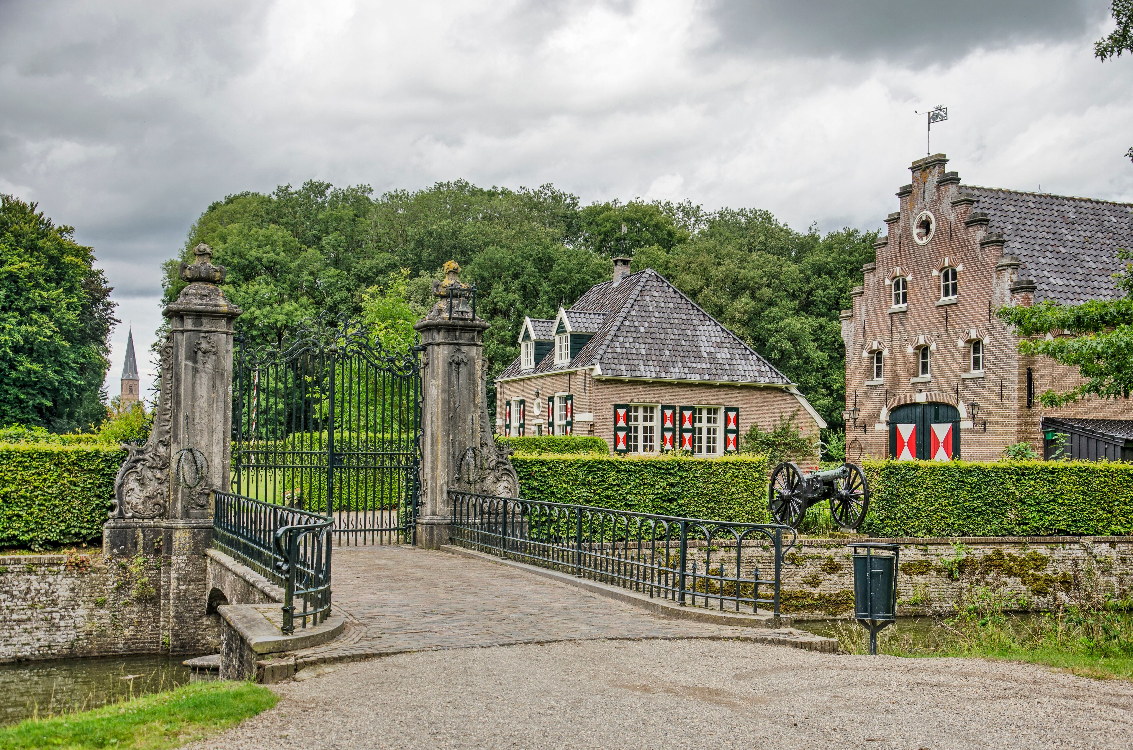 Wijhe,The Netherlands, August 7, 2021: bridge, gate and historic buildings of De Gelder estate with a vista towards the town's church tower in the distance