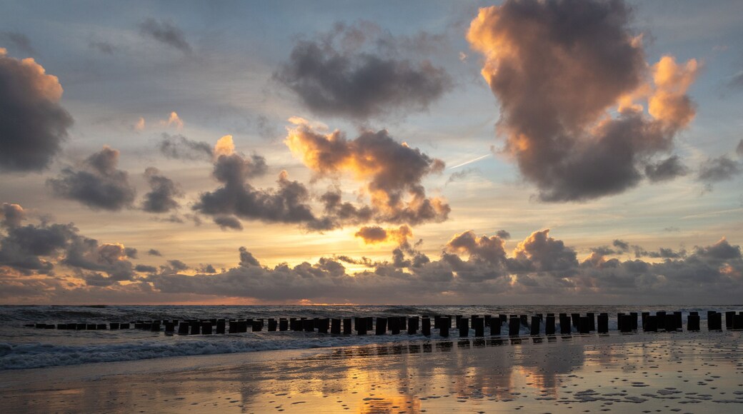 Sunset with colorful sky and clouds and wooden posts at Westenschouwen, Zeeland, the Netherlands