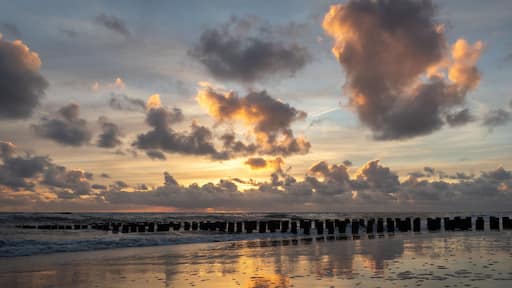 Sunset with colorful sky and clouds and wooden posts at Westenschouwen, Zeeland, the Netherlands