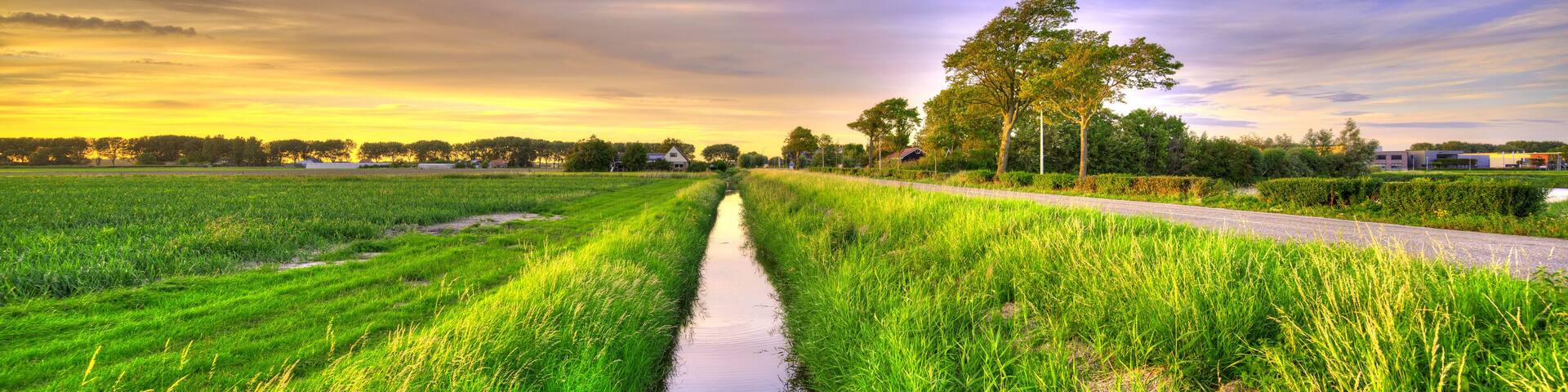 A small canal in a polder landscape in Holland at sunset.