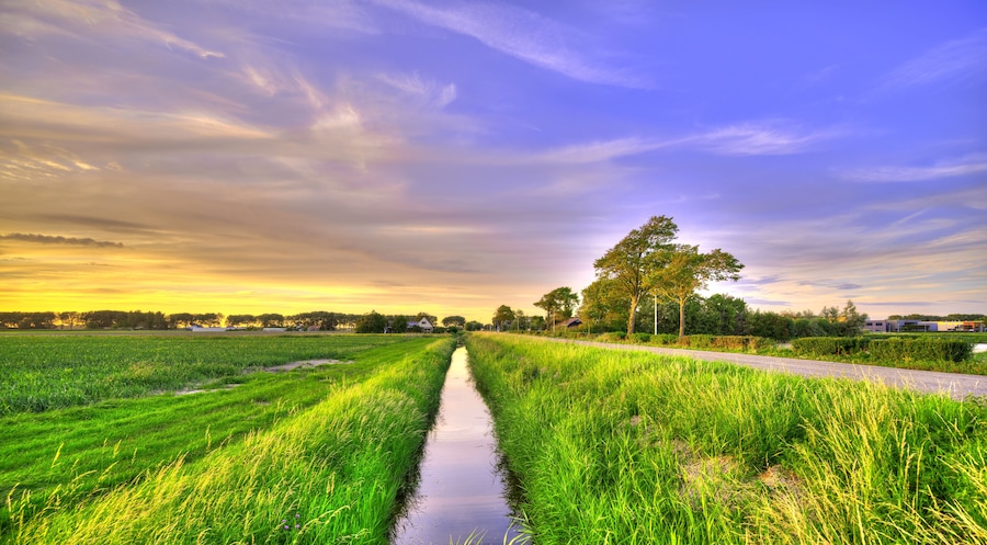 A small canal in a polder landscape in Holland at sunset.