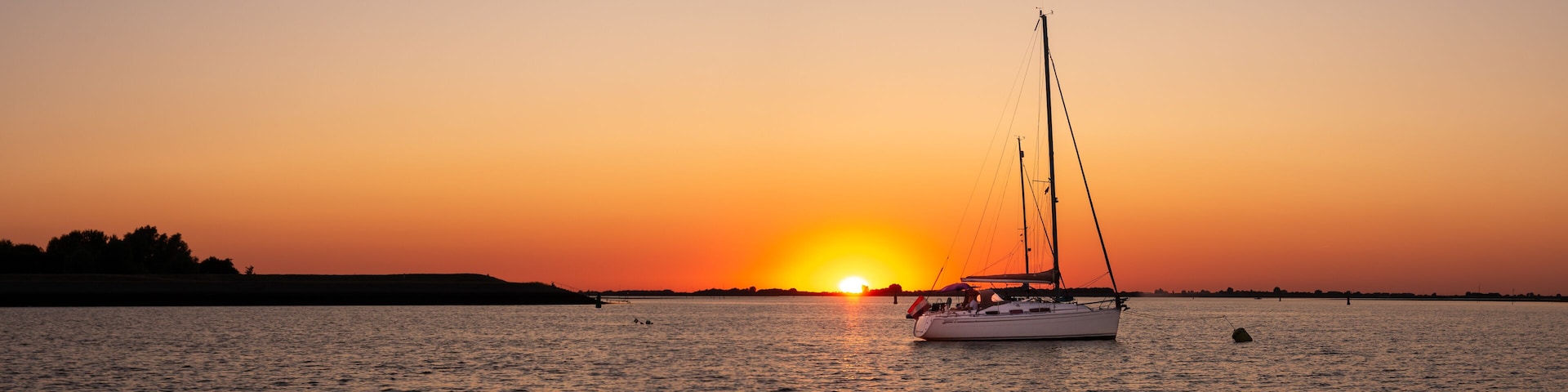 Sailboats moored at sunset on Krabbenkreek inlet, Oosterschelde National Park, Zeeland, Netherlands