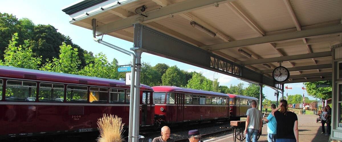 A vintage train at a station with people sitting at outdoor tables.