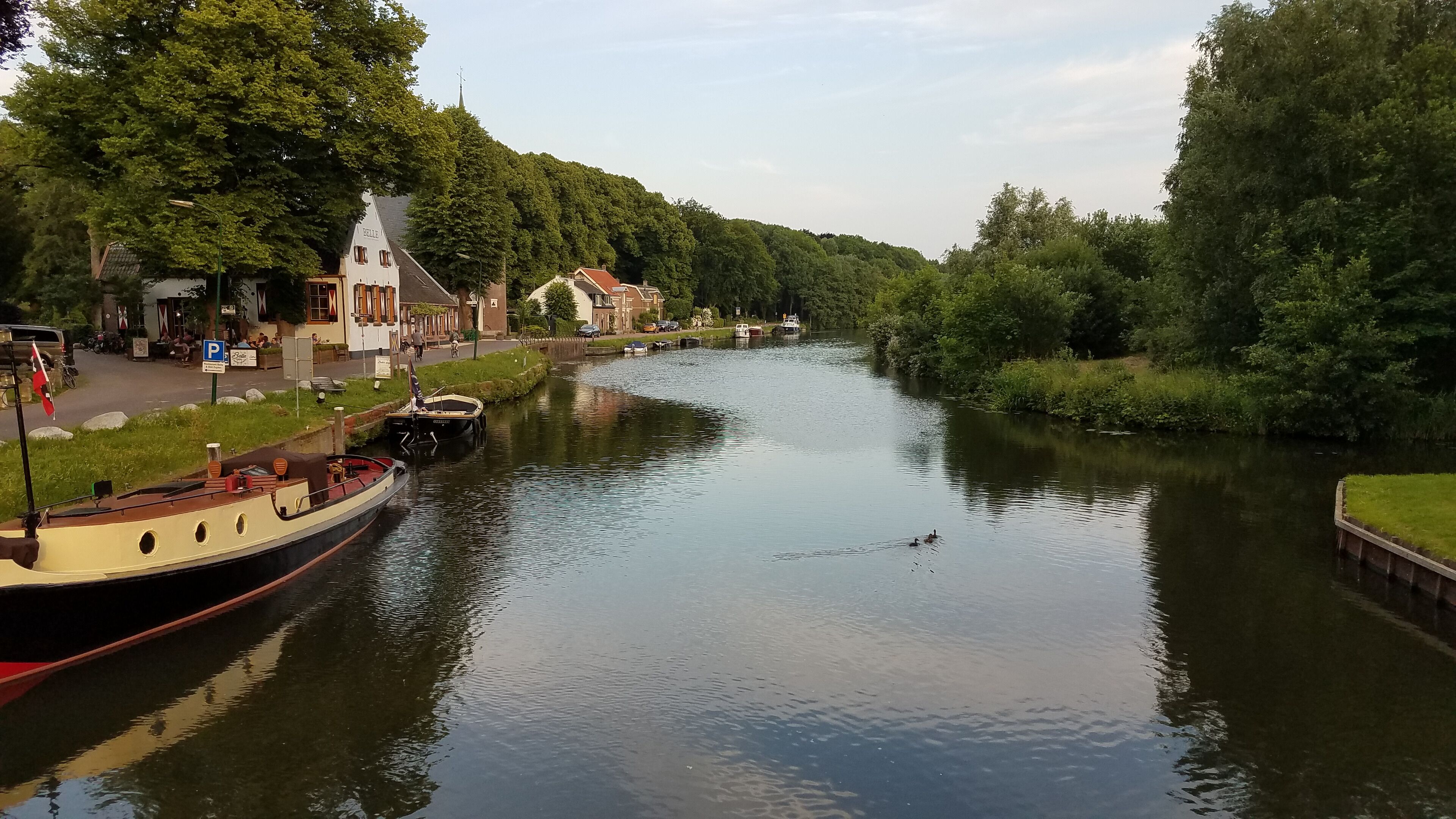 A calm river with boats, a church, and lush greenery.