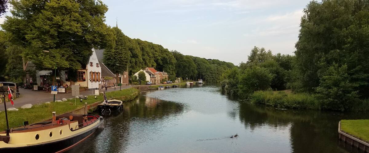 A calm river with boats, a church, and lush greenery.