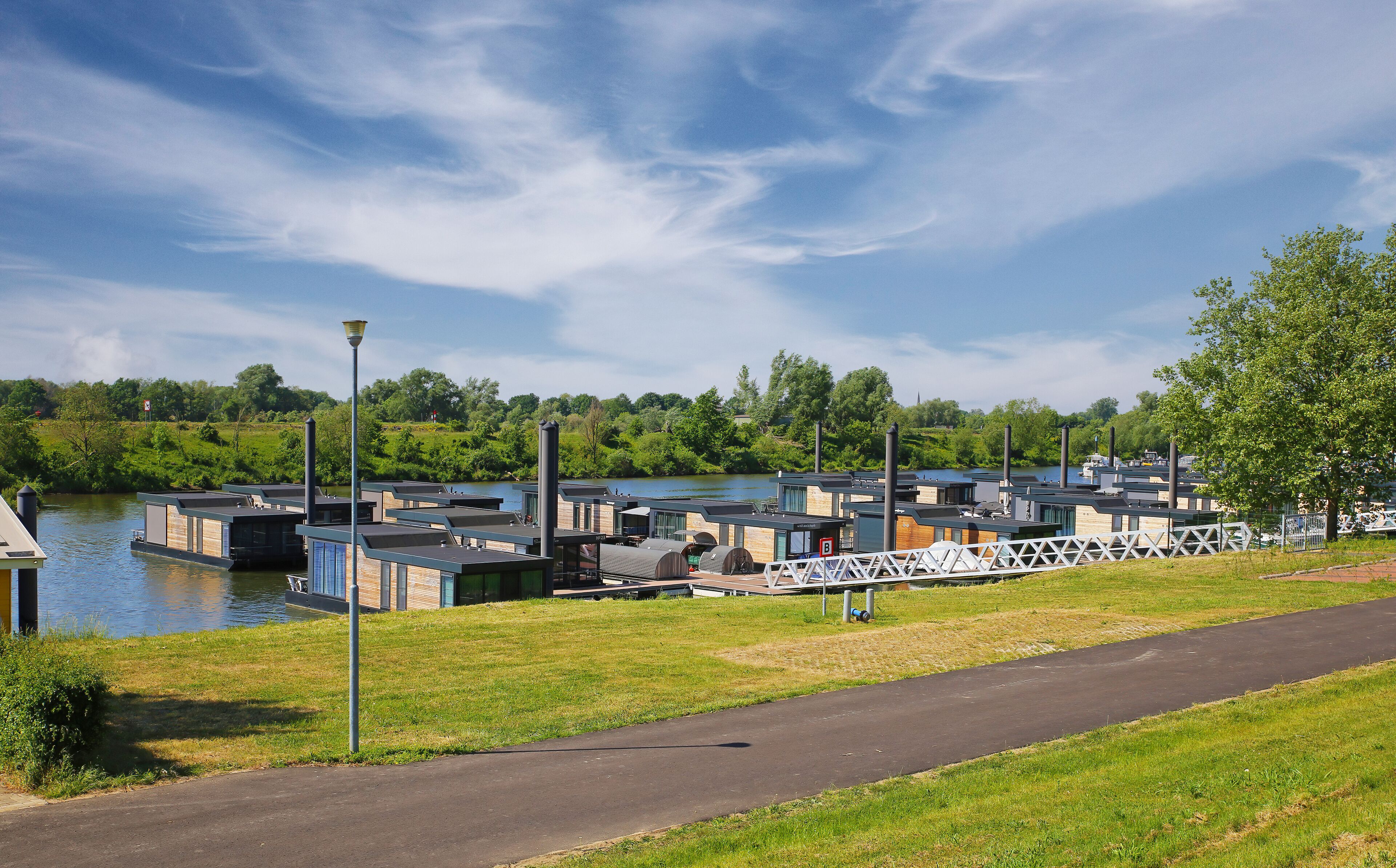 A riverside area with floating houses and a pedestrian path.