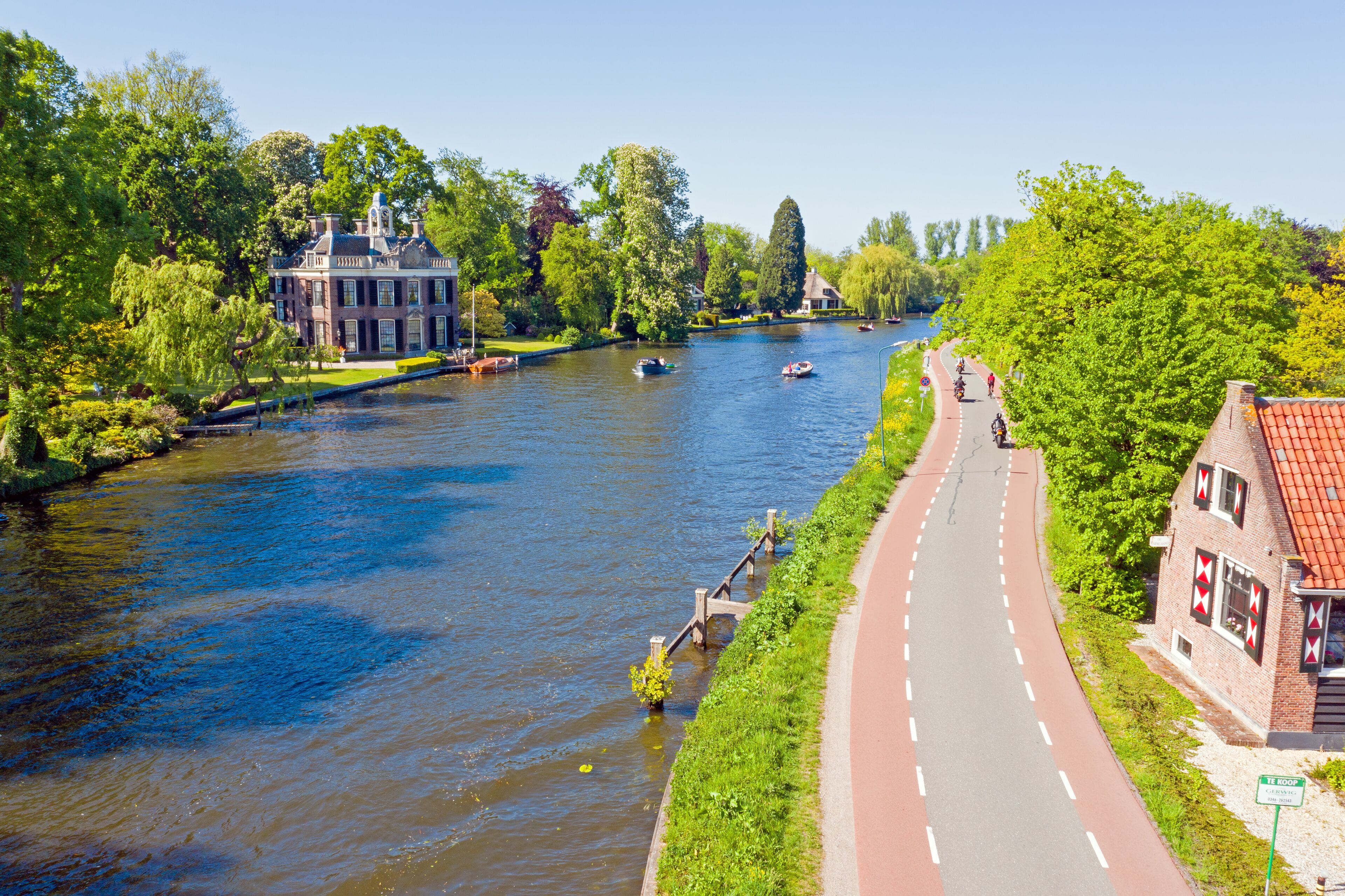 A river with boats, a brick building, and a paved path alongside.