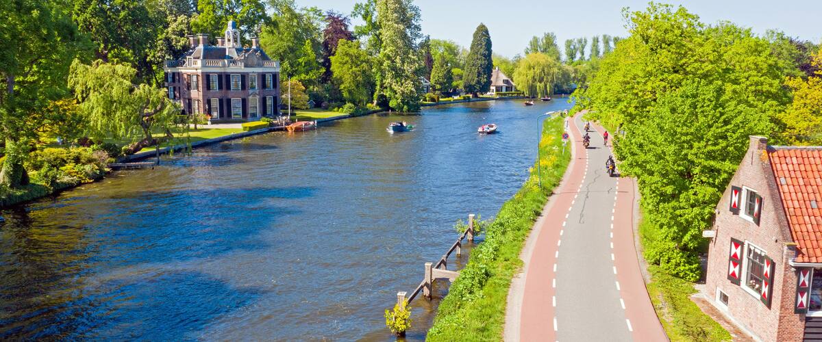 A river with boats, a brick building, and a paved path alongside.