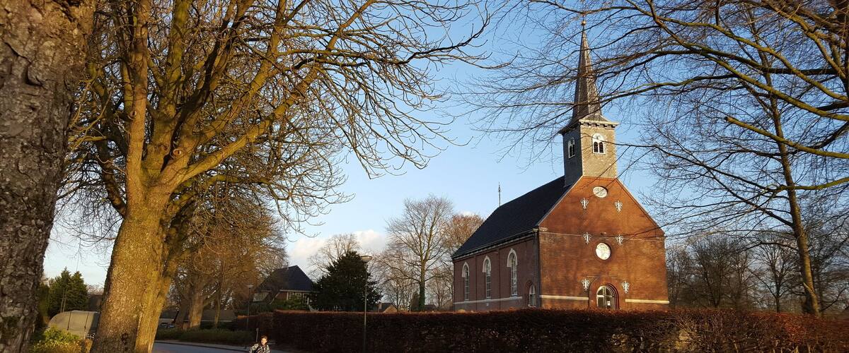 A cyclist on a red bike lane beside a church with a clock tower.