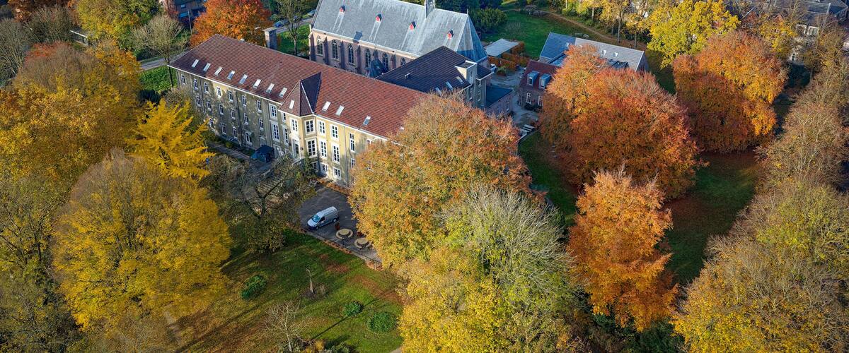 An aerial view of a town with autumn-colored trees, a prominent church, and residential houses.