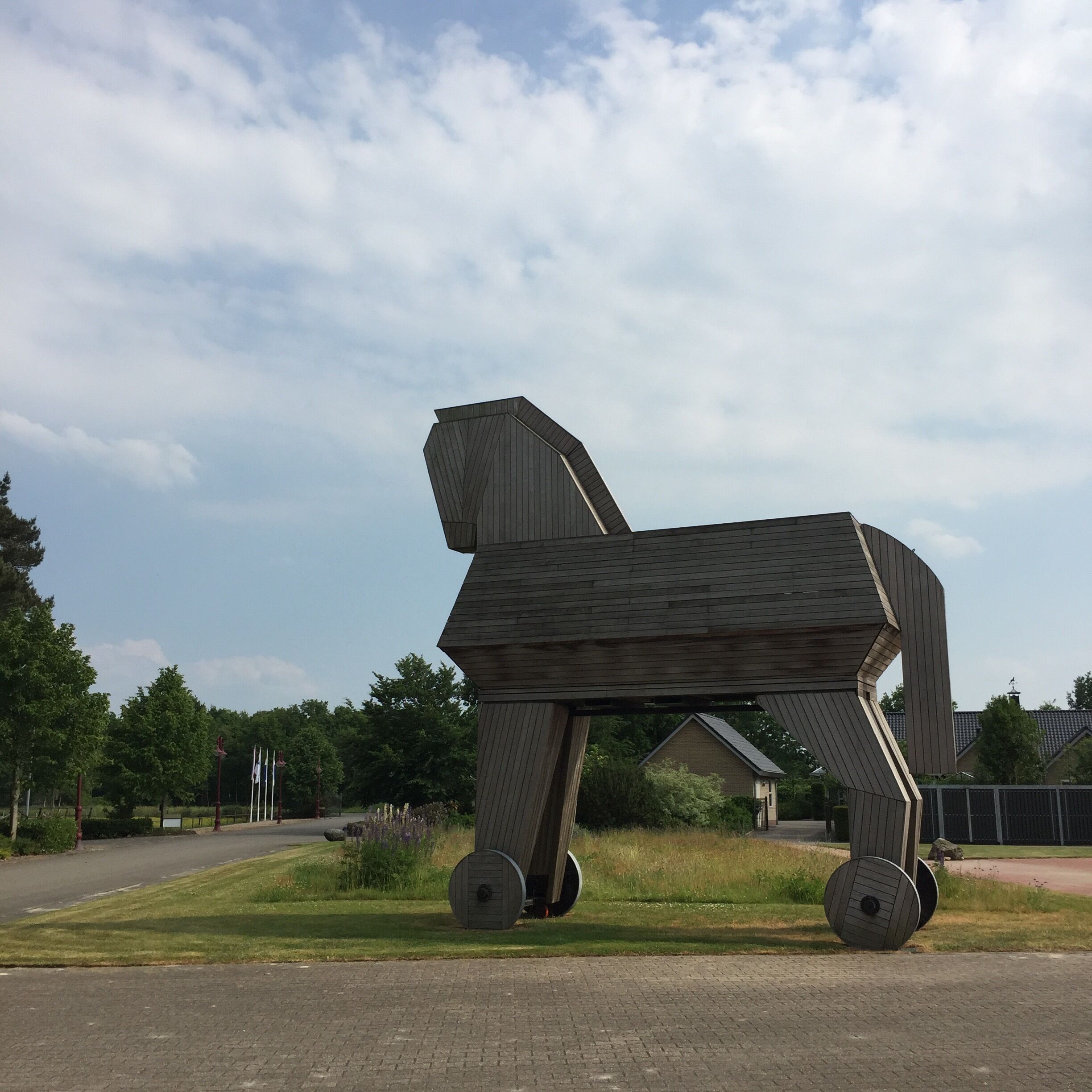 A large wooden sculpture of a horse in a grassy area.