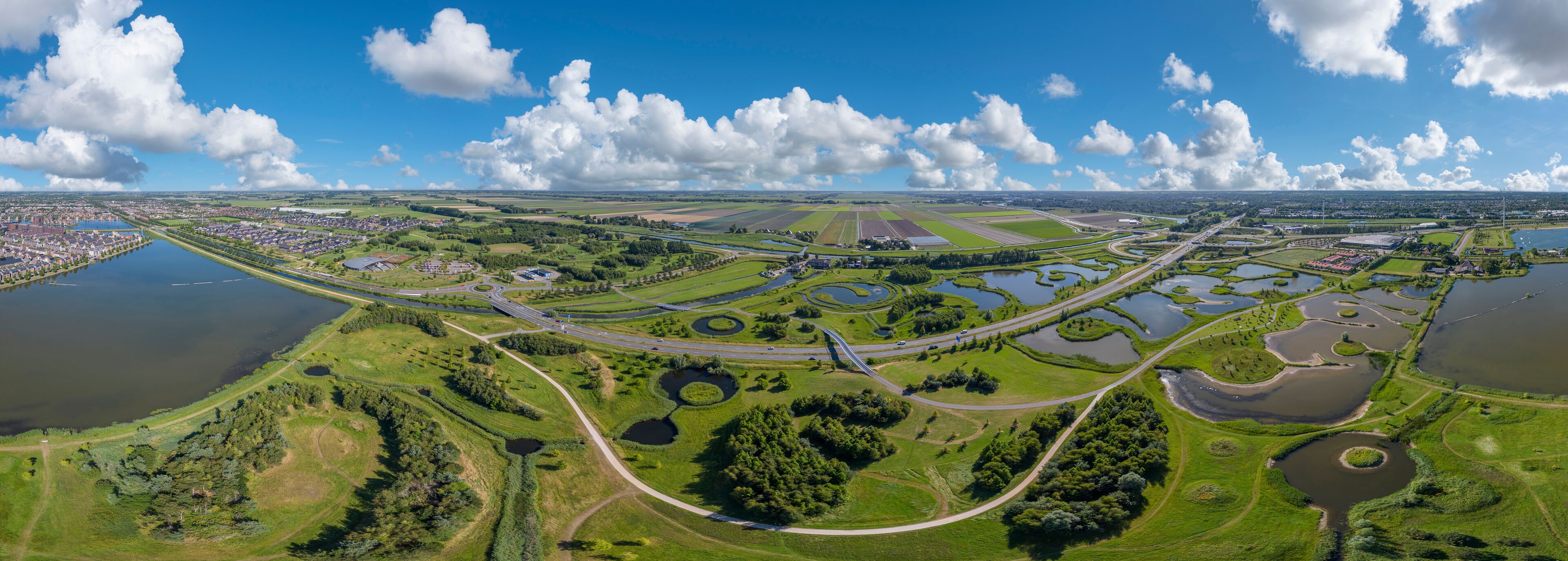 An aerial view of a town with a river, green fields, and a highway.