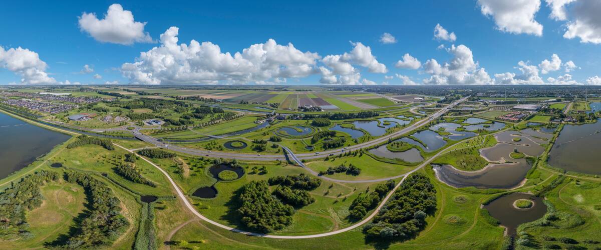 An aerial view of a town with a river, green fields, and a highway.