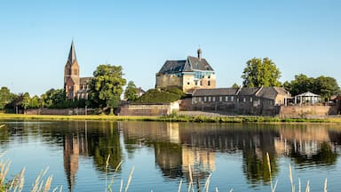 Un río tranquilo con una iglesia y un castillo al fondo.