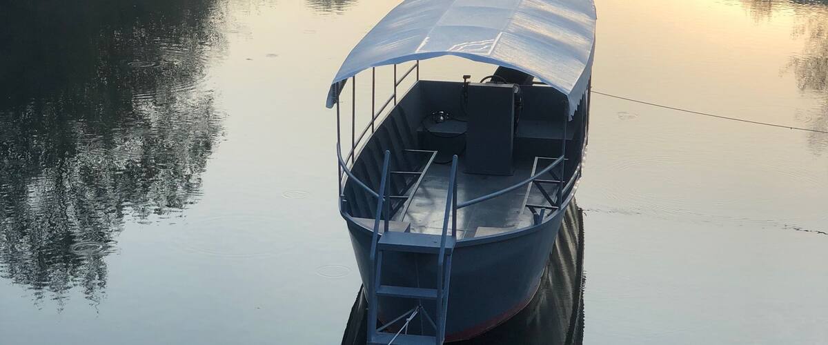 A boat anchored on a calm river with misty hills in the background.