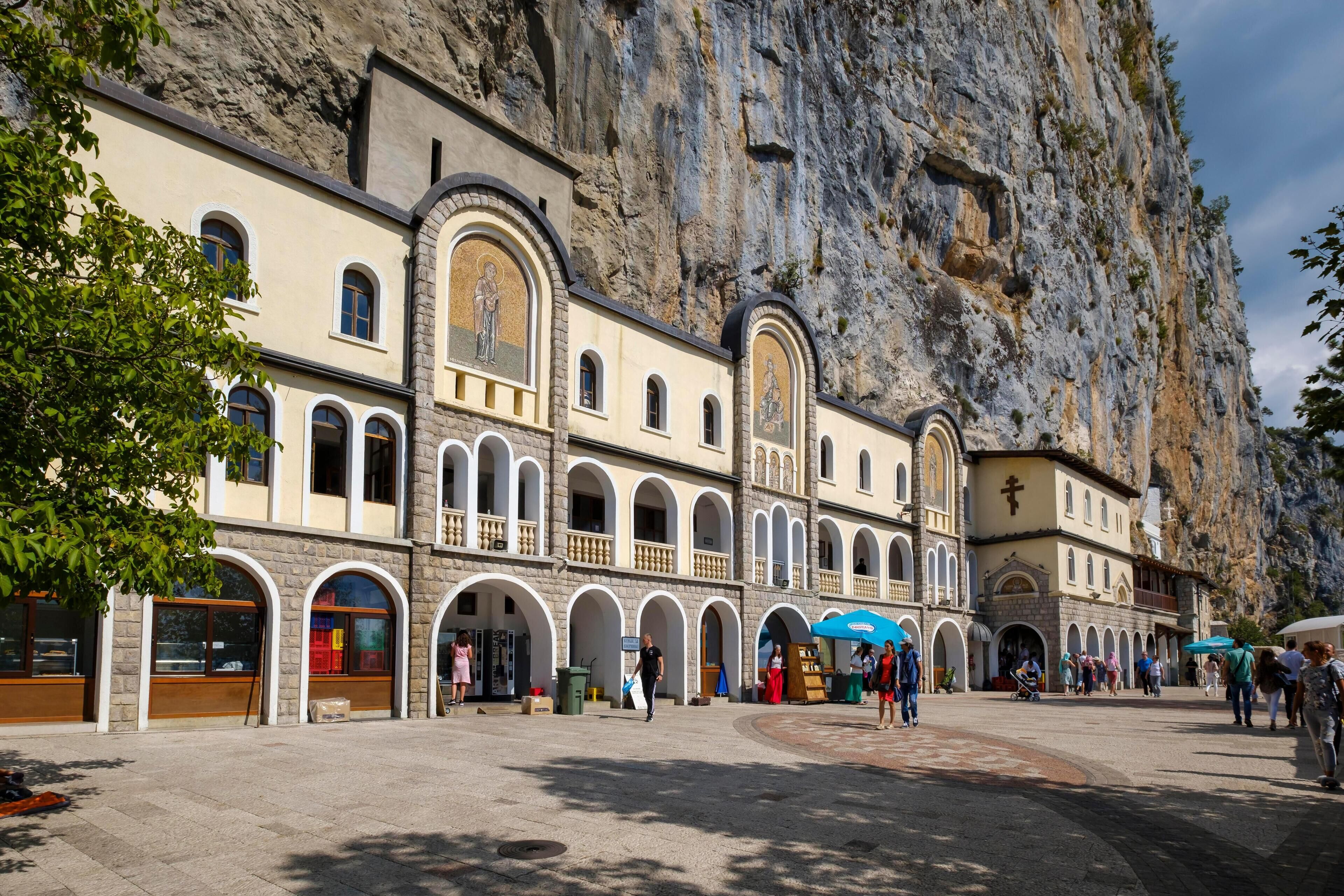 A historic church with arched windows and a large rock face behind it.
