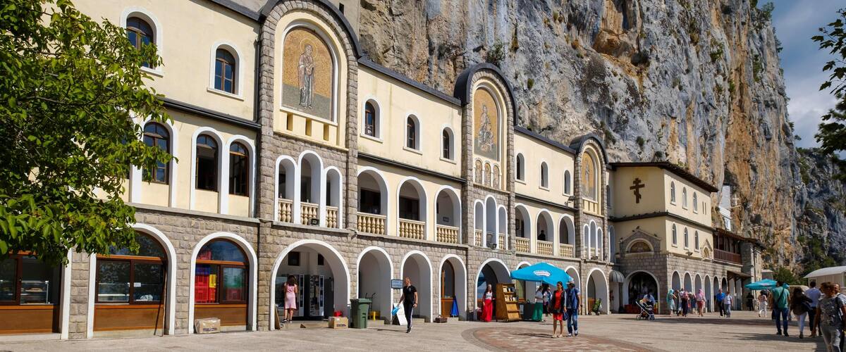 A historic church with arched windows and a large rock face behind it.