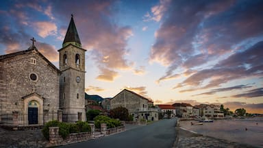 Uma igreja de pedra com uma torre sineira e um relógio, ao pôr do sol.