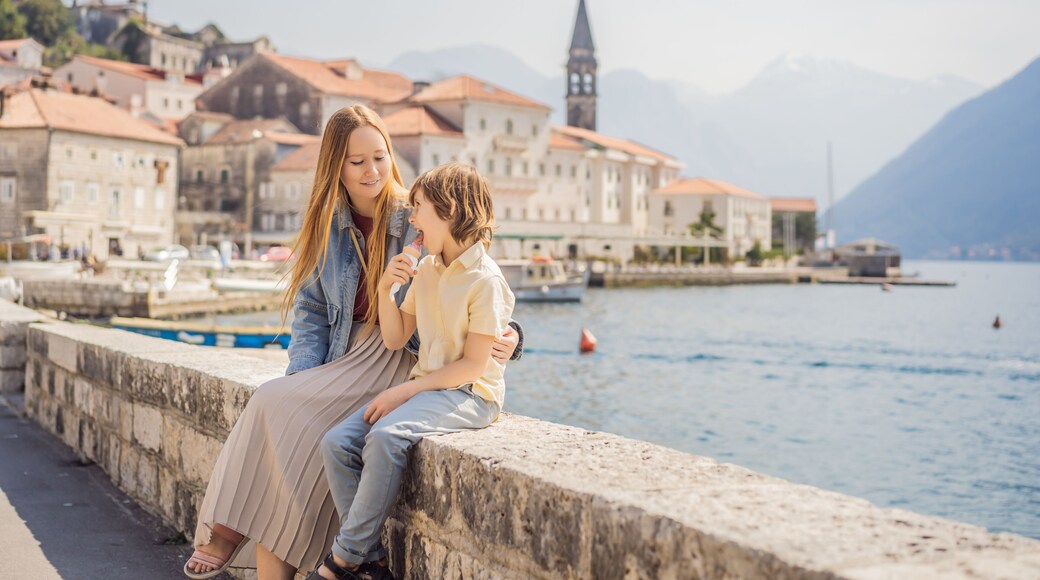 Mom and son tourists enjoying Colorful street in Old town of Perast on a sunny day, Montenegro. Travel to Montenegro concept. Scenic panorama view of the historic town of Perast at famous Bay of Kotor