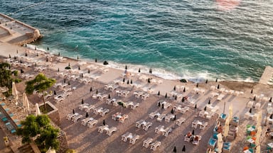 A beach with rows of sun loungers and umbrellas, a stone walkway, and the ocean.
