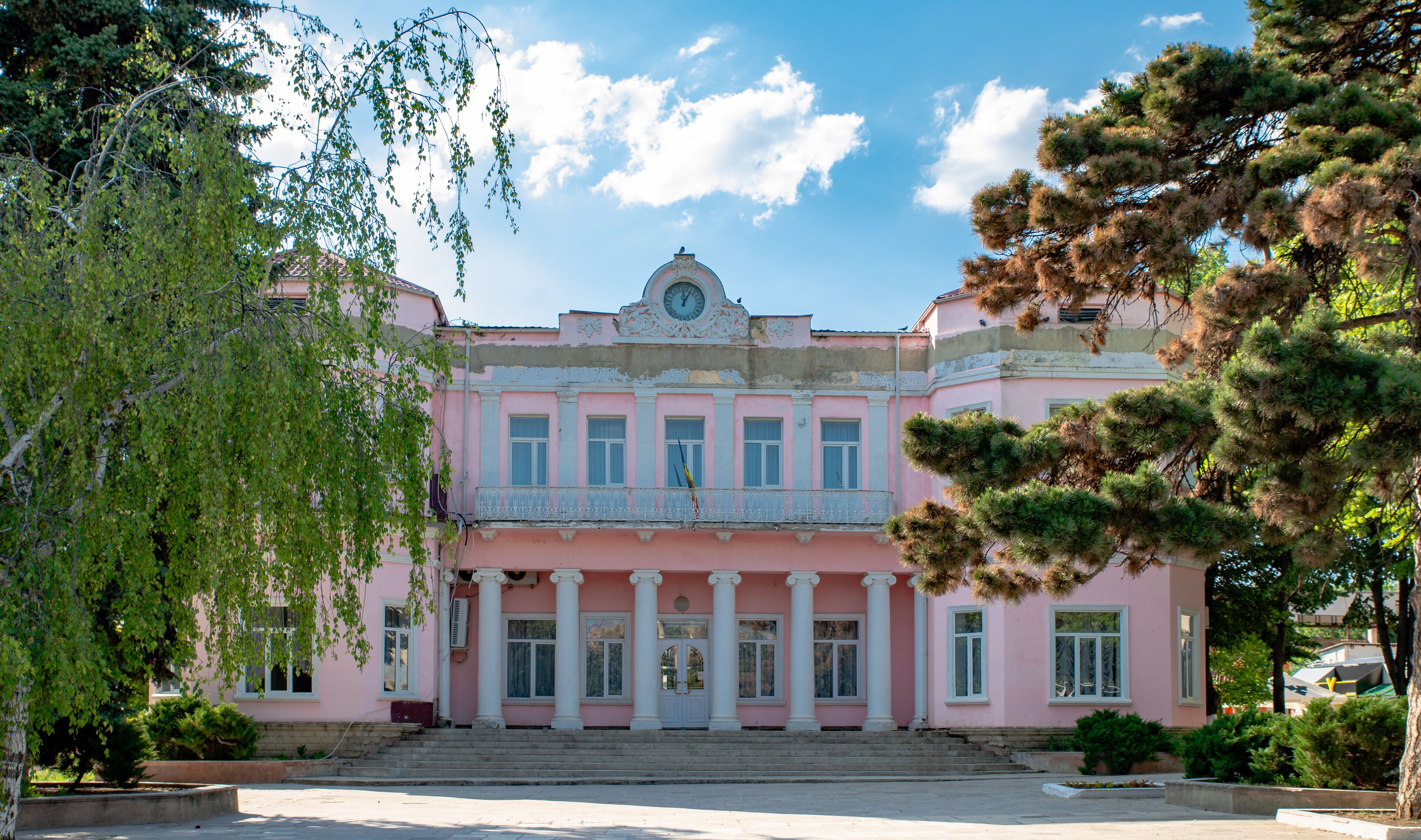 A pink building with columns and a clock.