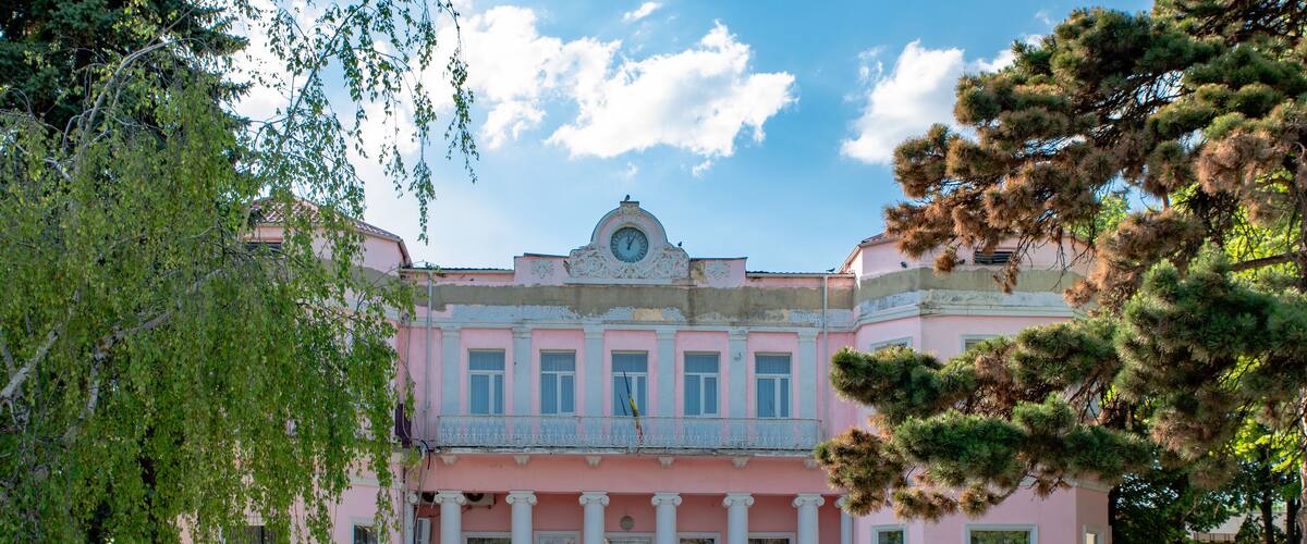 A pink building with columns and a clock.