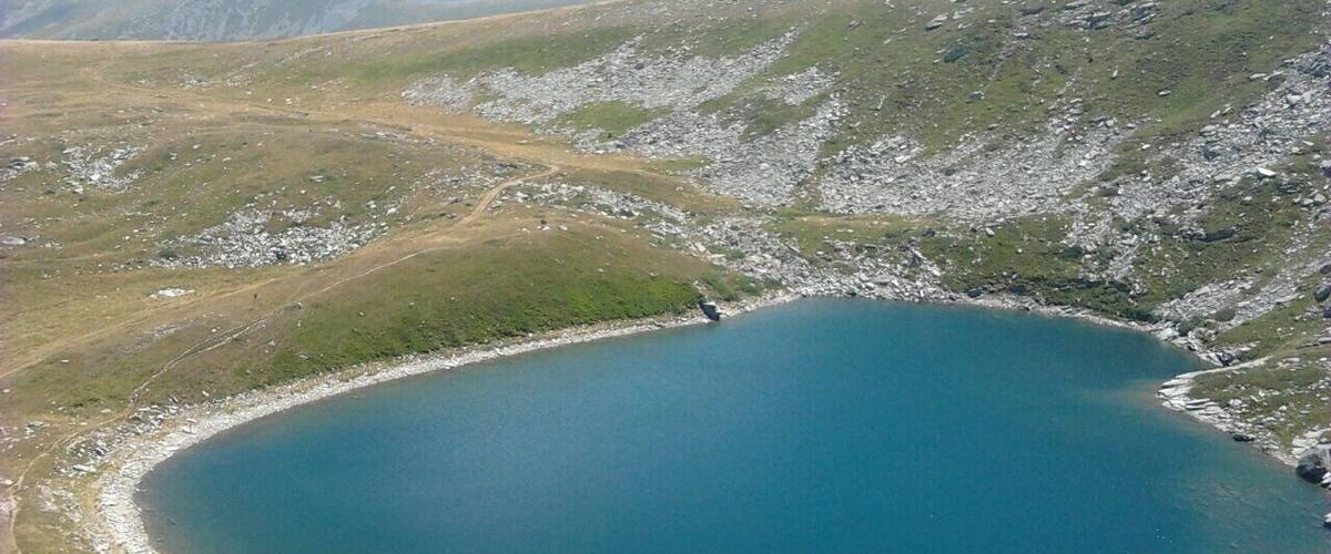 A circular lake surrounded by rocky terrain and sparse vegetation.