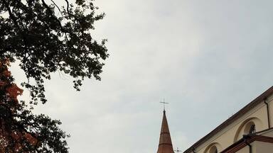 A church with a bell tower and a large tree with autumn leaves.