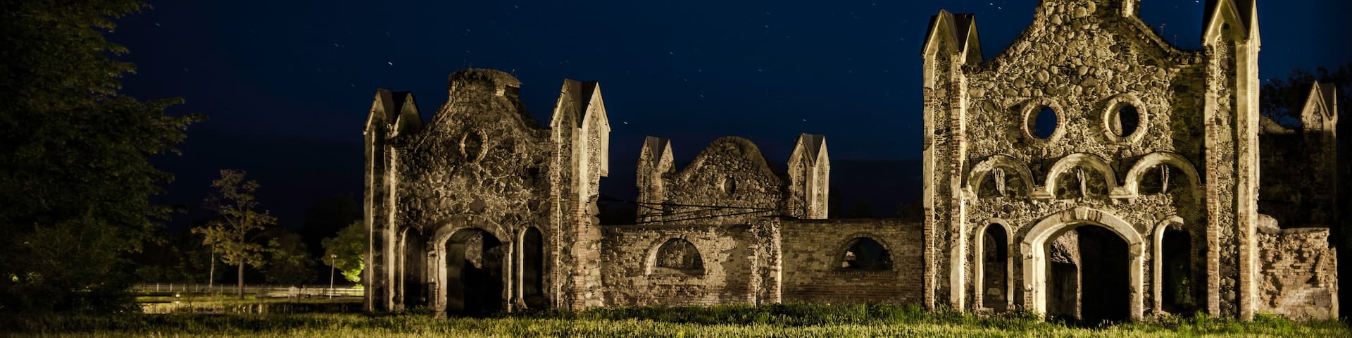 A historic stone building with arched doorways and a starry night sky.