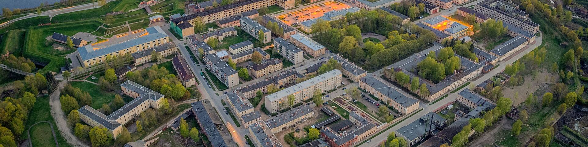 An aerial view of a large campus with multiple buildings, a river, and surrounding green fields.
