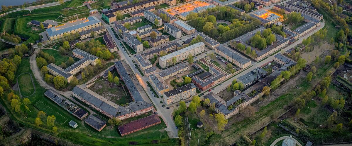 An aerial view of a large campus with multiple buildings, a river, and surrounding green fields.
