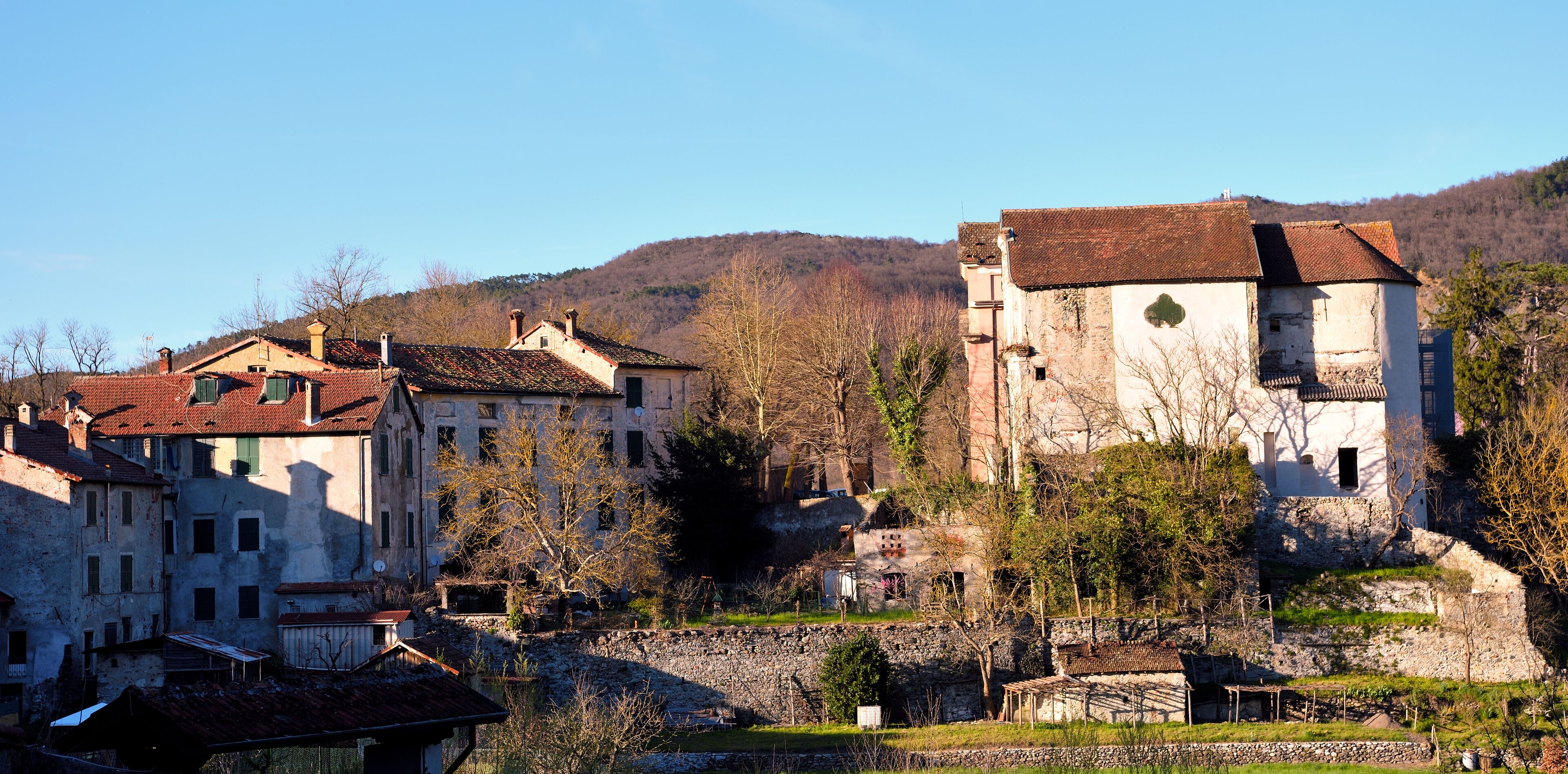 A historic village with stone buildings and a hillside in the background.