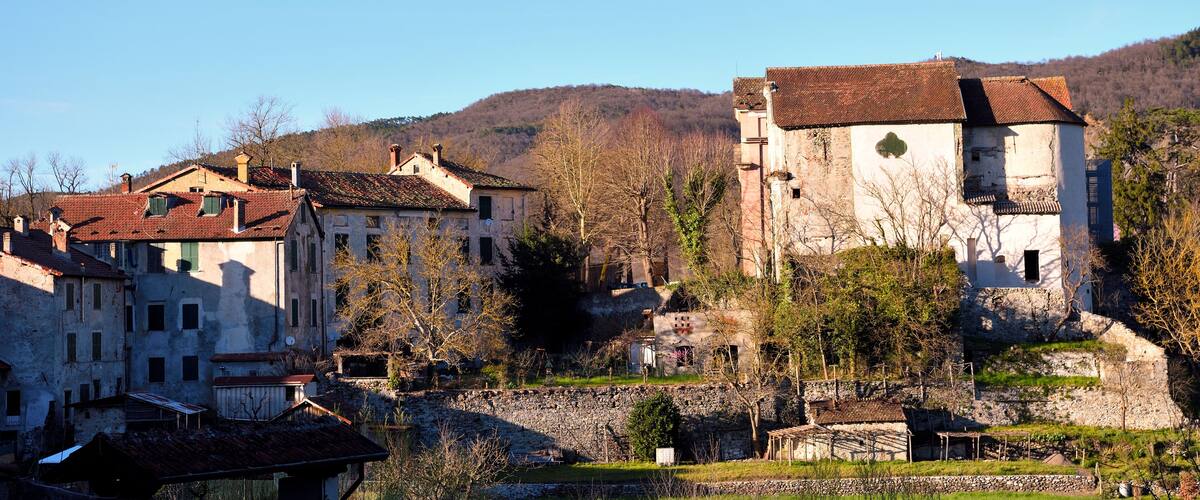 A historic village with stone buildings and a hillside in the background.