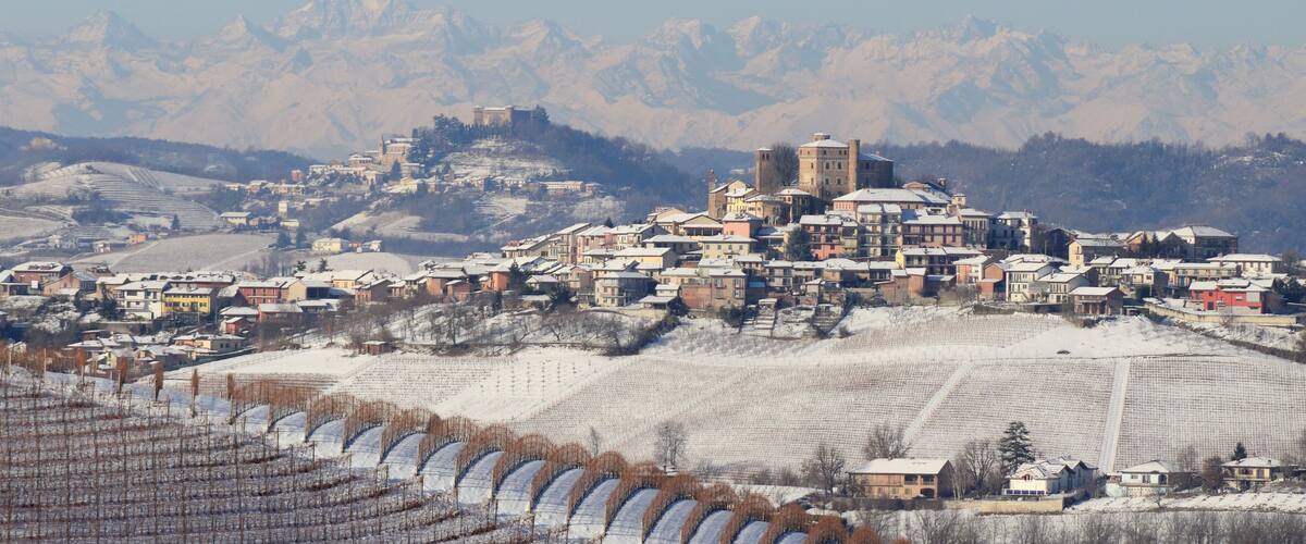 A snow-covered town with a prominent castle-like structure in the center, surrounded by mountains.