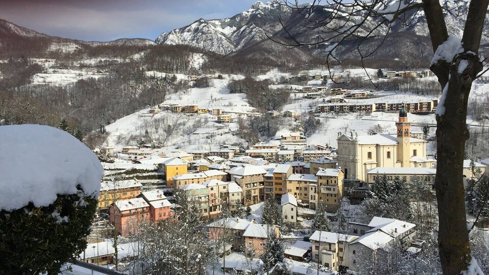 A snow-covered village with buildings and mountains in the background.