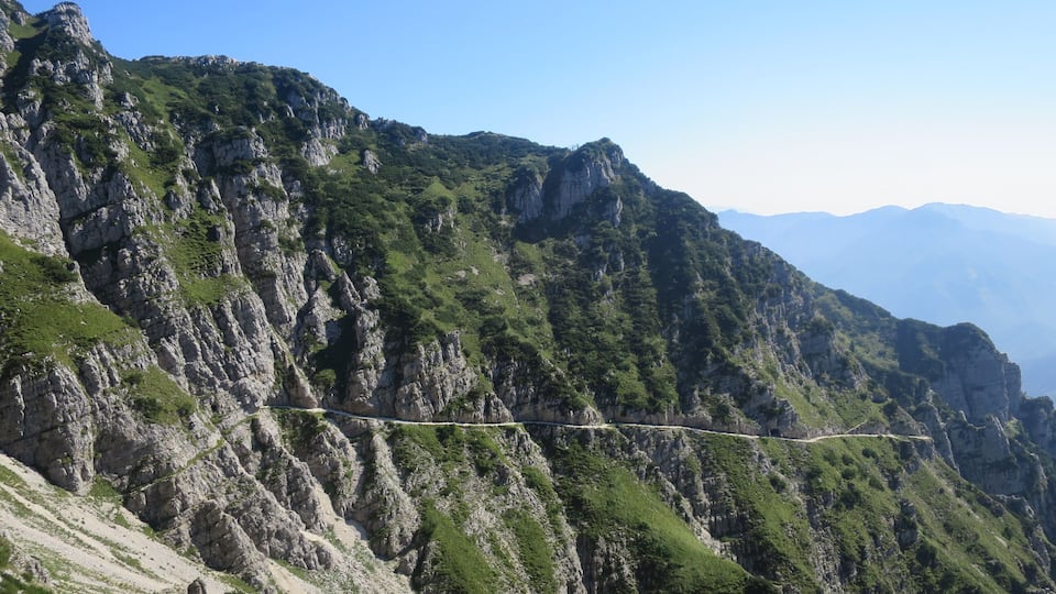A mountainous landscape with a narrow road winding through rocky terrain.