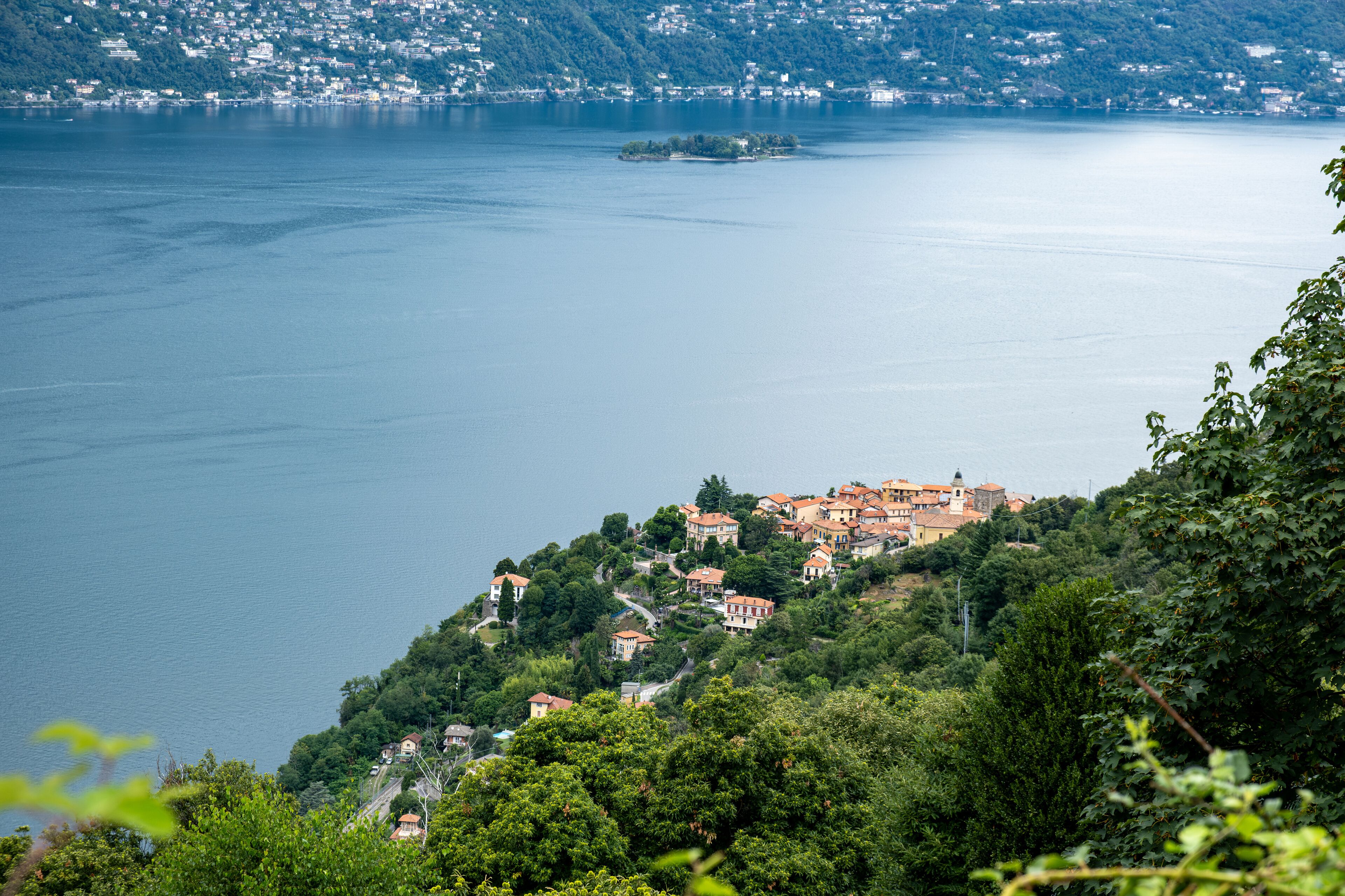 A coastal village with terraced houses on a hillside overlooking a calm lake.