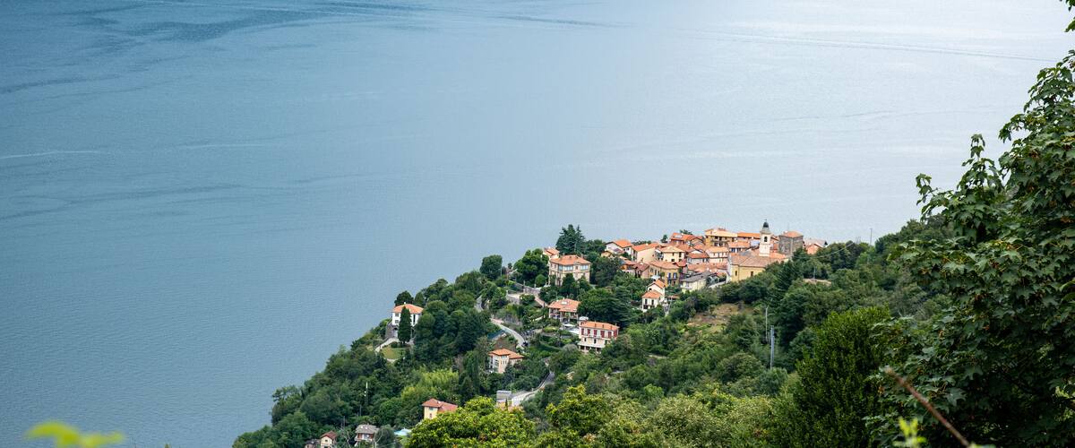 A coastal village with terraced houses on a hillside overlooking a calm lake.