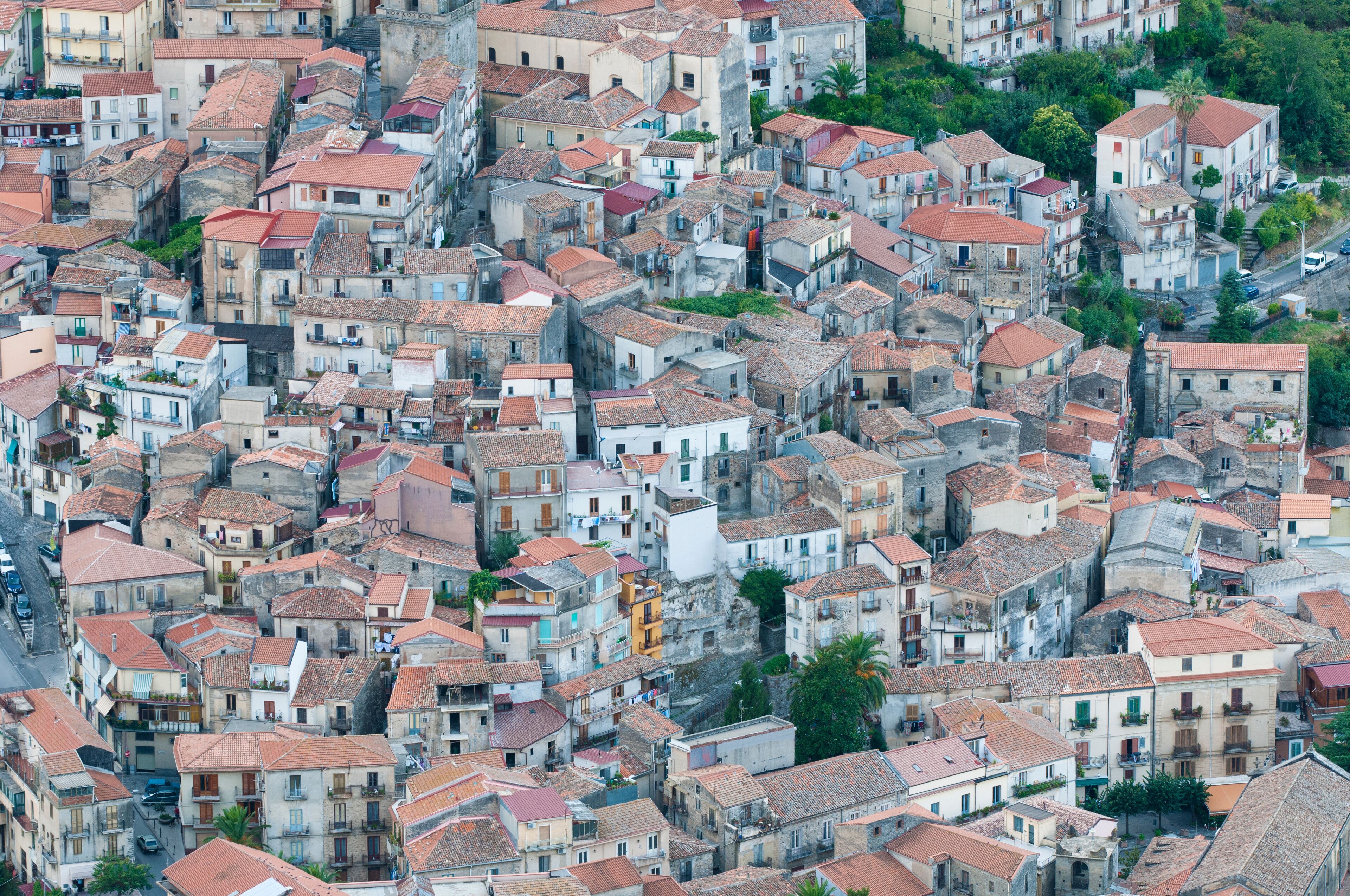A densely packed urban area with closely built structures, red-tiled roofs, and narrow streets.
