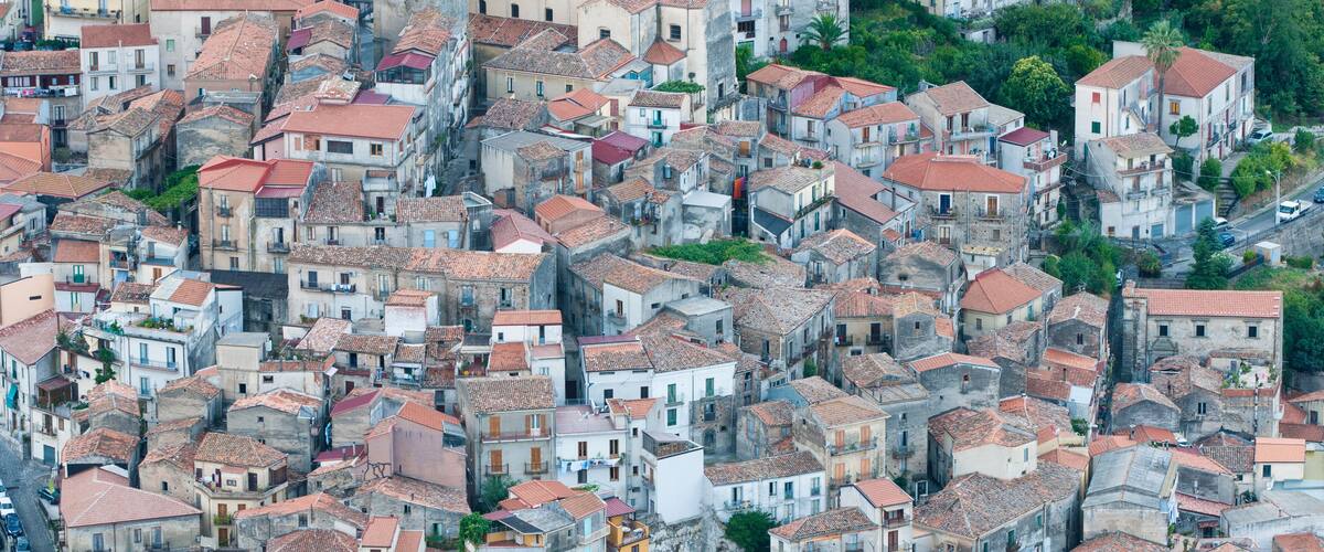 A densely packed urban area with closely built structures, red-tiled roofs, and narrow streets.