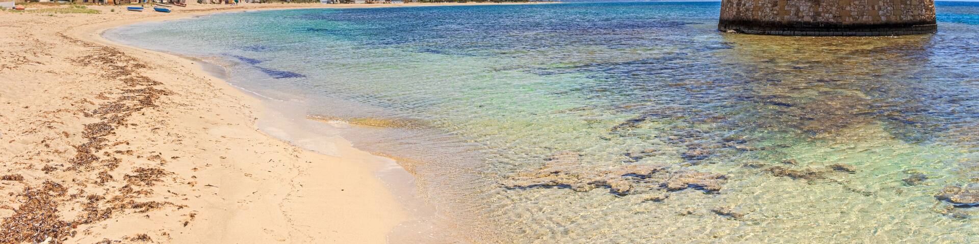 Salento coast: Torre Pali in Apulia, Italia.The ruined sixteenth century watchtower of Torre Pali, surrounded by crystal clear water, appears in the blue water, a few metres away from the coast.
