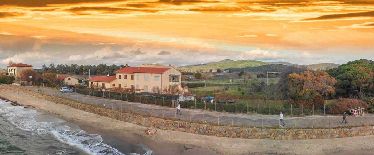 A coastal town with a historic tower, modern buildings, and a stone wall along the beach.