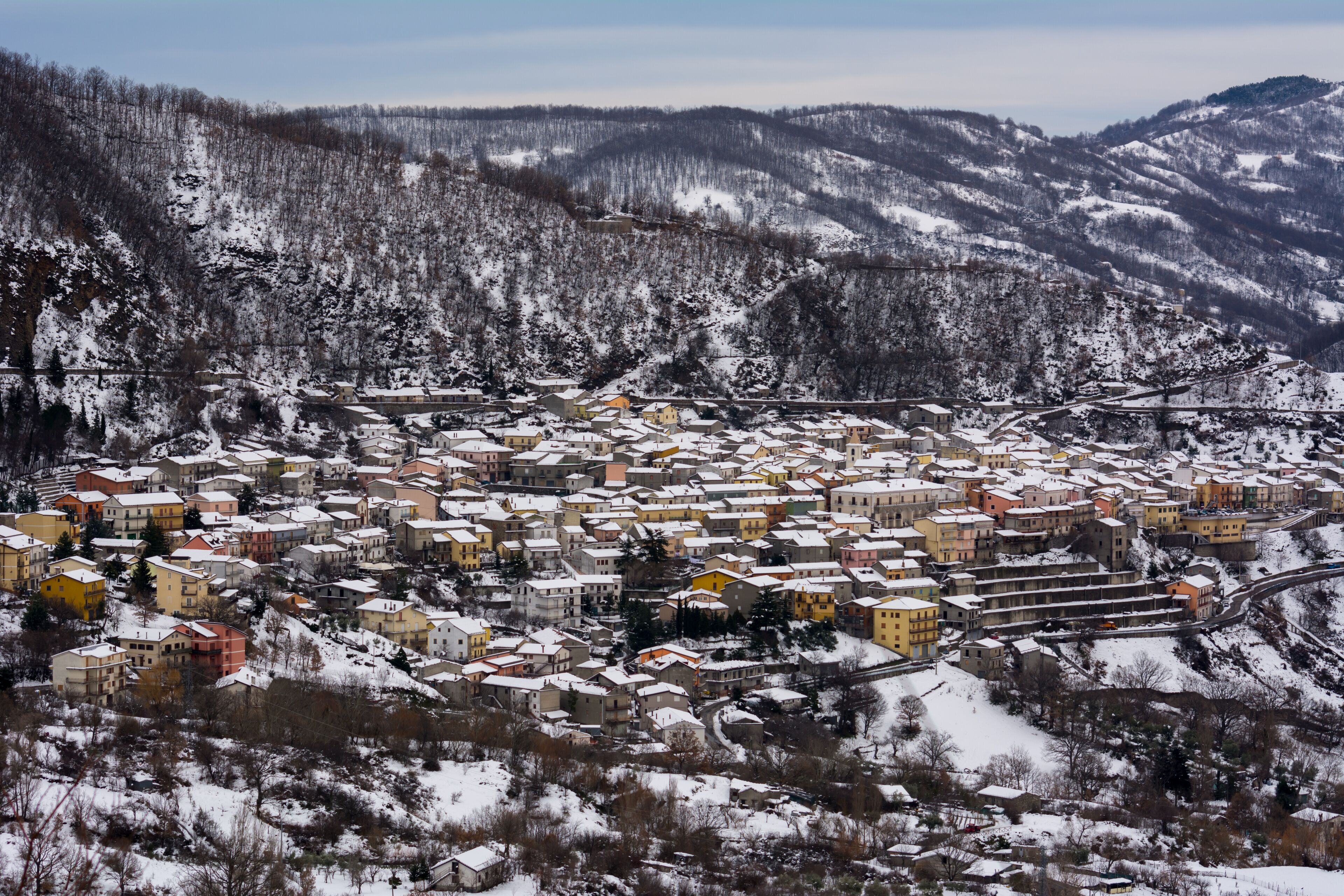 A snow-covered town nestled in a valley with mountains in the background.