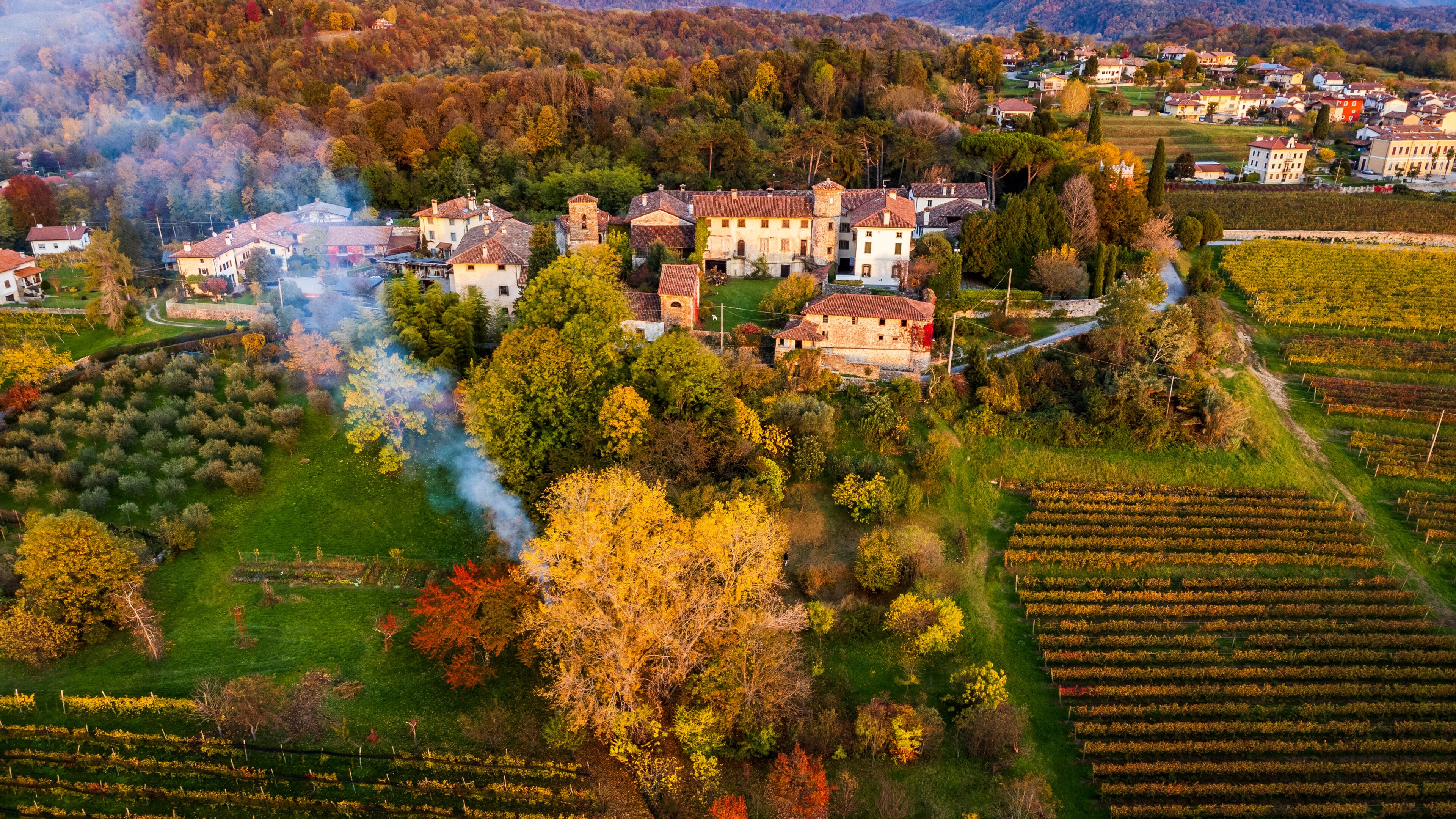 Autumnal magic and emotions on the ancient village. Between vineyards and colorful woods. Friuli. Top view