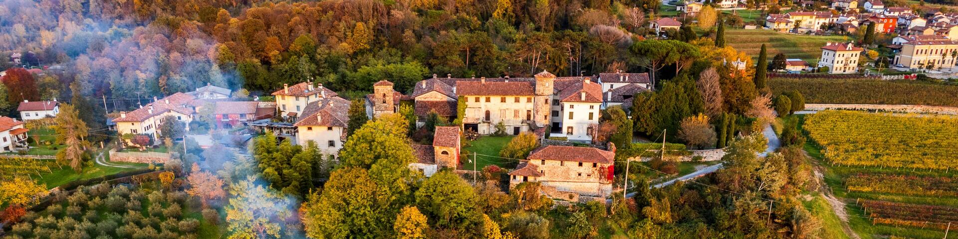 Autumnal magic and emotions on the ancient village. Between vineyards and colorful woods. Friuli. Top view