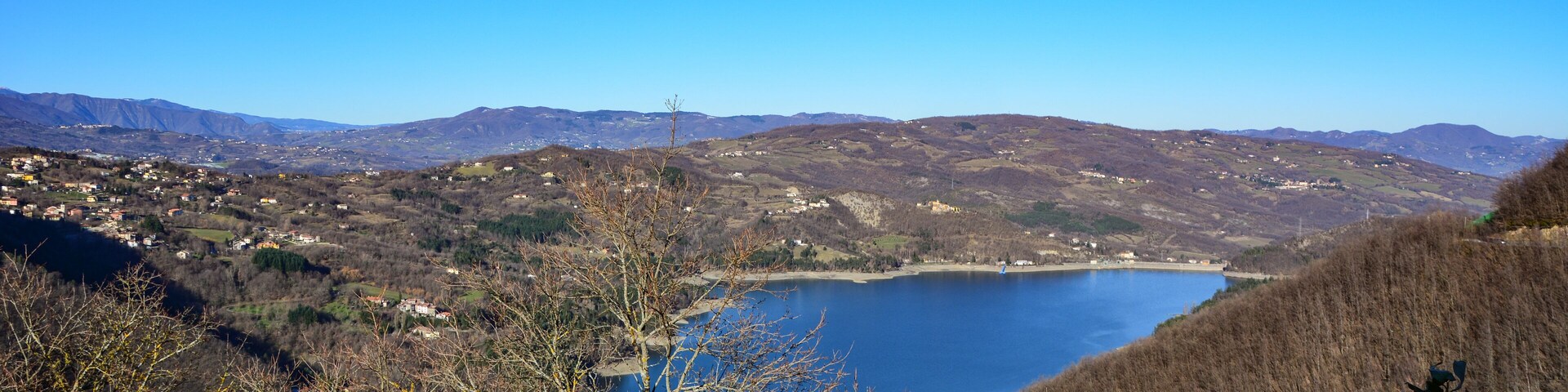 Un lago rodeado de colinas y vegetación escasa.