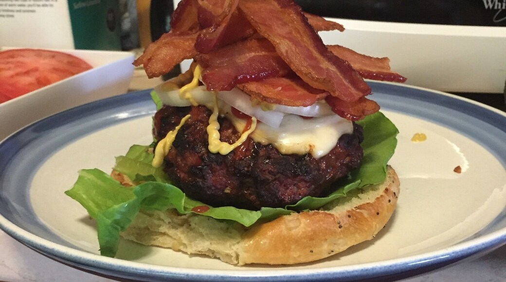 Onion roll with lettuce, burger with different kinds of seasonings and provolone cheese in the middle topped with more provolone cheese, jalapeño ketchup, German mustard, onions and a heaping stack of bacon strips! #Delicious #homemade