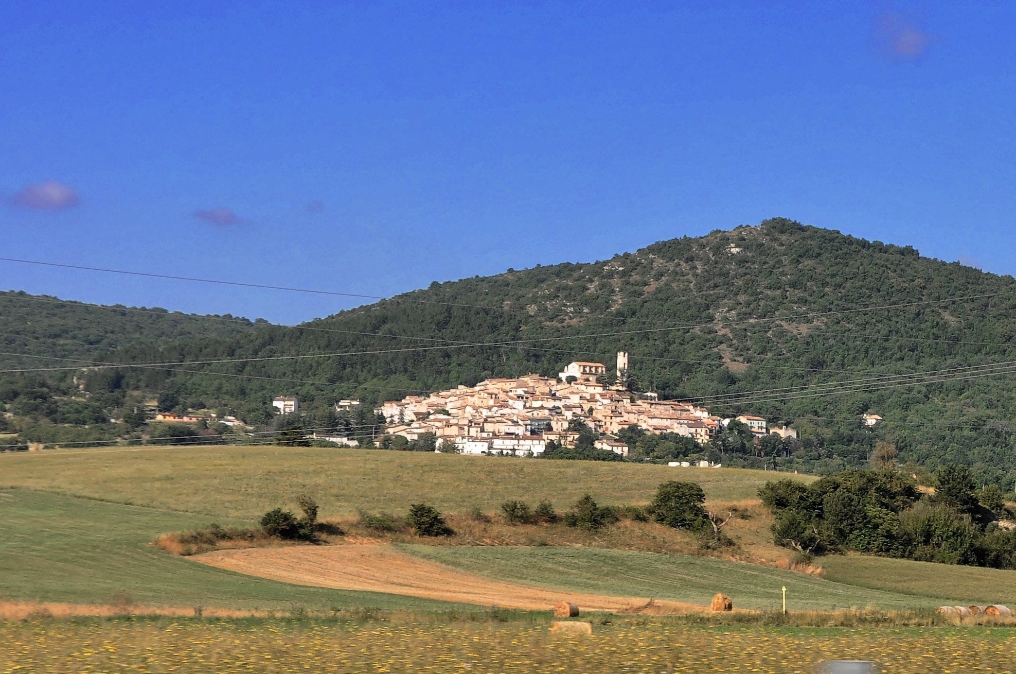 A village on a hillside with fields in the foreground.